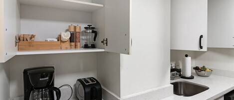 Une cuisine moderne avec des meubles blancs, une machine à café, un grille-pain et un évier.