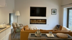 Una sala de estar moderna con un sofá, una televisión y un comedor con mesa.