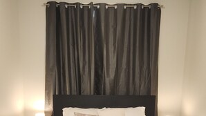 A neatly made bed with white linens, two bedside tables with lamps, and a dark headboard. - Setons private & cozy suite (Calgary)