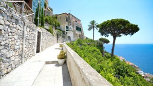 Ein Steinweg führt zu einem Gebäude mit Blick aufs Meer.