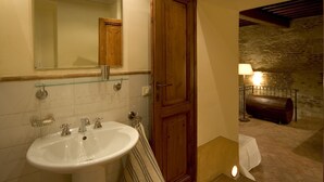 Un baño con un lavamanos blanco, un espejo y una puerta de madera.