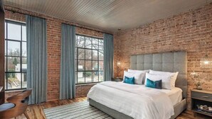 Un dormitorio con una cama grande, una pared de ladrillo y vistas a través de una ventana.