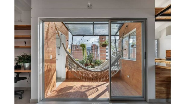 Um interior moderno com uma grande porta de vidro deslizante que dá para uma área de pátio externo.