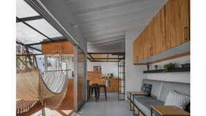 Uma cozinha moderna com armários de madeira, um espaço de bar e uma área de estar com sofá e mesas.