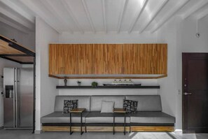 Un salon moderne avec un canapé gris, deux tables d’appoint et un meuble en bois placé au-dessus.