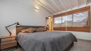 Quarto moderno com uma cama grande, abajures, mesa de cabeceira e uma janela ampla com vista.