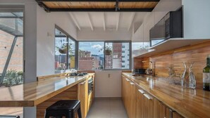 Cozinha moderna com bancadas de madeira, fogão embutido e uma grande janela com vista para a cidade.