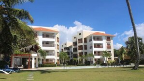 Un resort con edificios de varios pisos, una piscina y palmeras.