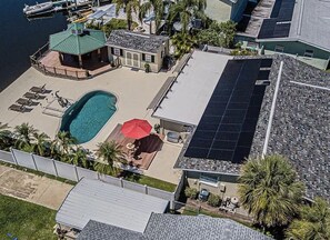 Une propriété résidentielle dotée d’une piscine, de panneaux solaires et d’un patio couvert.