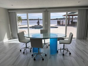 Une salle de réunion moderne, dotée d’une table en verre et de quatre chaises, avec de grandes fenêtres donnant sur une piscine et un espace extérieur.