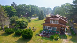 Une maison en bois à deux étages, dotée d’une terrasse et d’un espace salon extérieur.