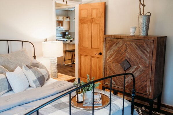 A bedroom with a bed, bedside table, lamp, and a wooden cabinet. - Urban Cottage (Buffalo City)