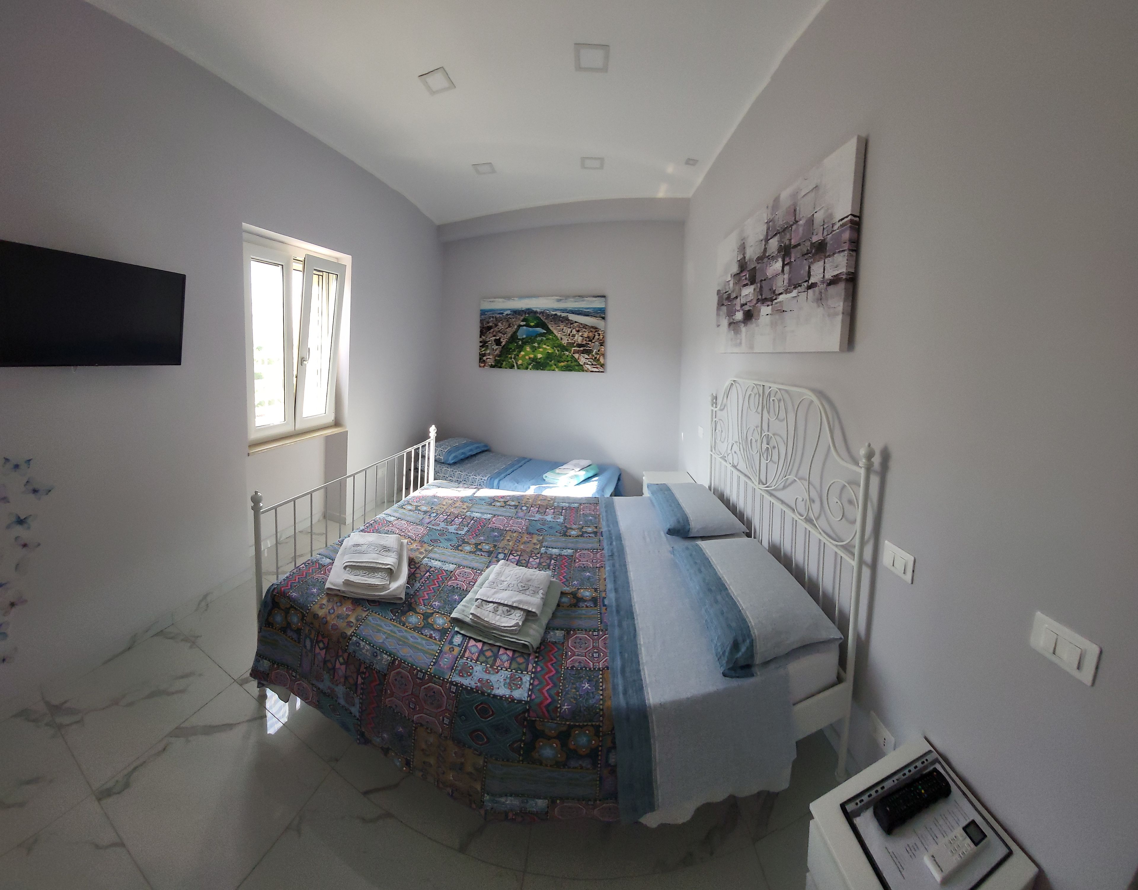 Une chambre à coucher avec un lit, une fenêtre, un tableau et une table de chevet.