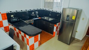 A compact kitchen with a refrigerator, a toaster, and a sink.