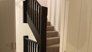 Uma escadaria com corrimão preto e degraus revestidos com carpete bege.