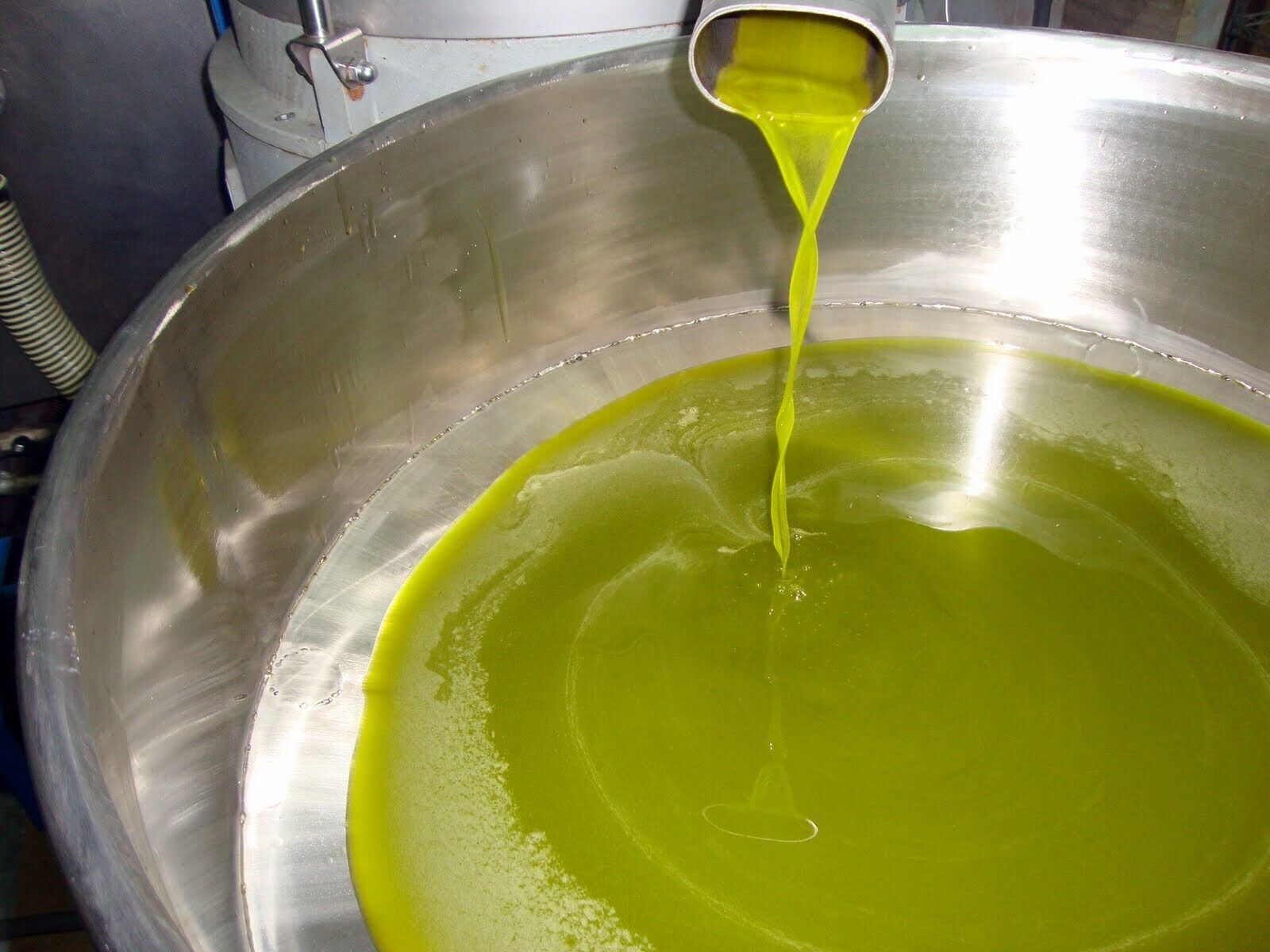 Un grand récipient métallique dans lequel on verse un liquide jaunâtre.