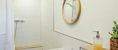 A modern bathroom with a shower, a sink, and a mirror.