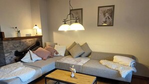 A modern living room with a grey sectional sofa, a wooden coffee table, and a white rug. - Vacation cottage Ferber (Wiesbaum)