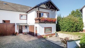 A two-story house with a balcony, a wooden gate, and a paved driveway. - Vacation cottage Ferber (Wiesbaum)