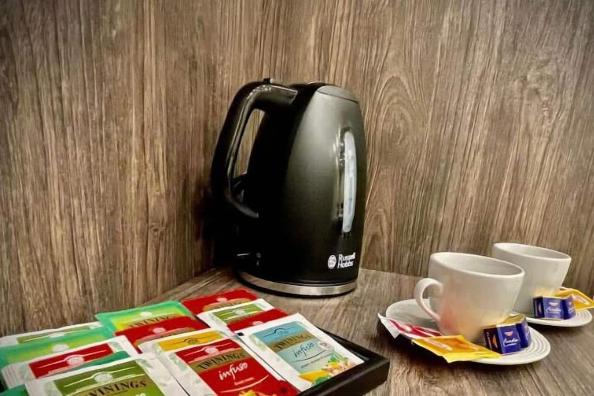 En köksdel med en svart elektrisk vattenkokare, två vita koppar och ett fat med tepåsar.