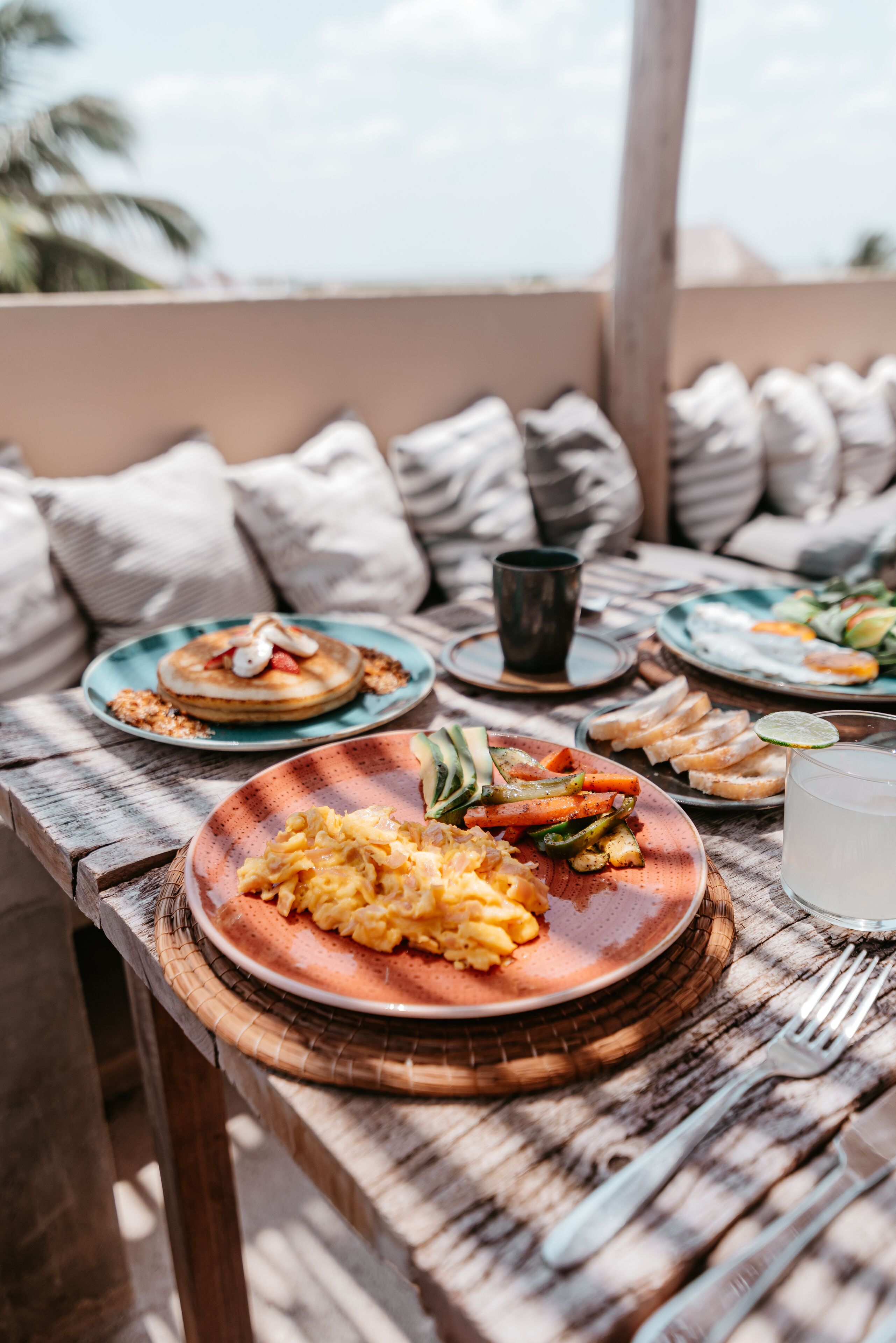 A wooden table with plates of food, a glass of water, and a cup.