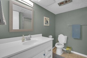 A bathroom with a white sink, mirror, and toilet.