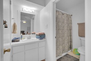A bathroom with a white vanity, a mirror, a sink, and a shower curtain. - Gated community with POOL on the beach (Matagorda)