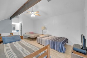 A bedroom with two beds, a ceiling fan, a desk with a computer, and a window. - Gated community with POOL on the beach (Matagorda)