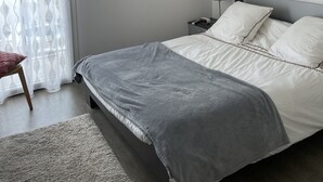 Une chambre à coucher avec un lit, une table de chevet, une lampe et une œuvre d’art accrochée au mur.