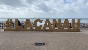 Un panneau placé sur la plage, affichant le hashtag #LAGANU et l’expression française « JAMAIS COMO AILLEURS ».
