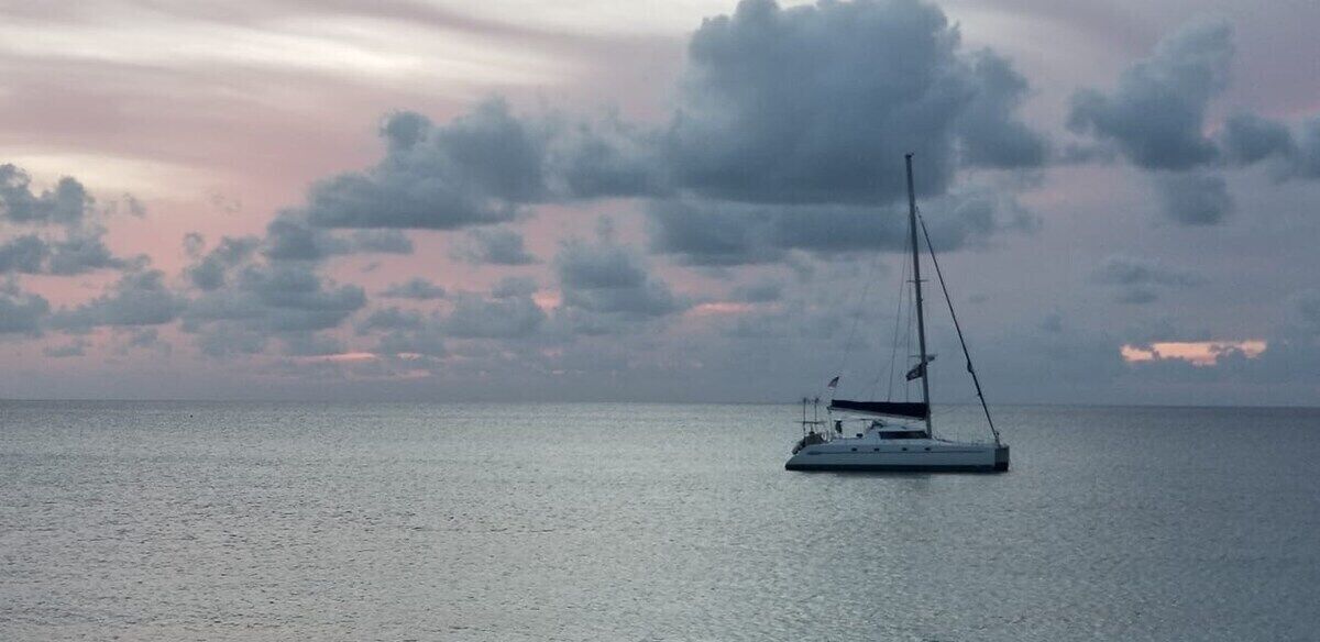 A sailboat on calm waters with a cloudy sky.