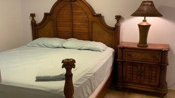 A bedroom with a wooden bed, a nightstand with a lamp, and a ceiling fan.