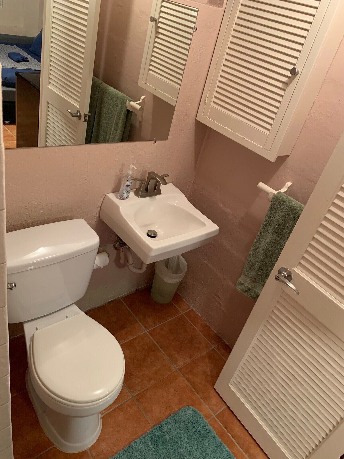 Et badeværelse med toilet, håndvask og spejl.