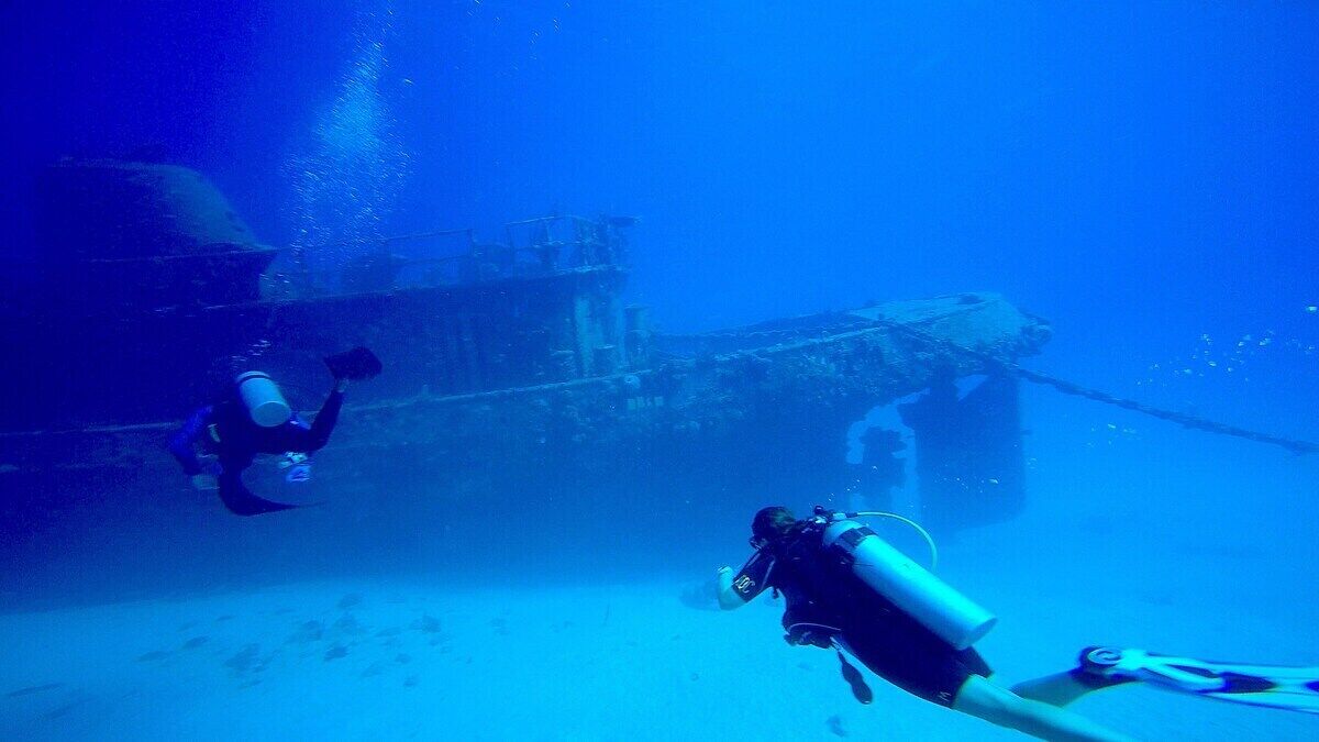 Une scène sous-marine où deux plongeurs explorent une structure immergée.
