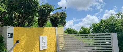Una entrada cerrada con un muro amarillo, un letrero que indica Windhime Estates y un portón blanco.