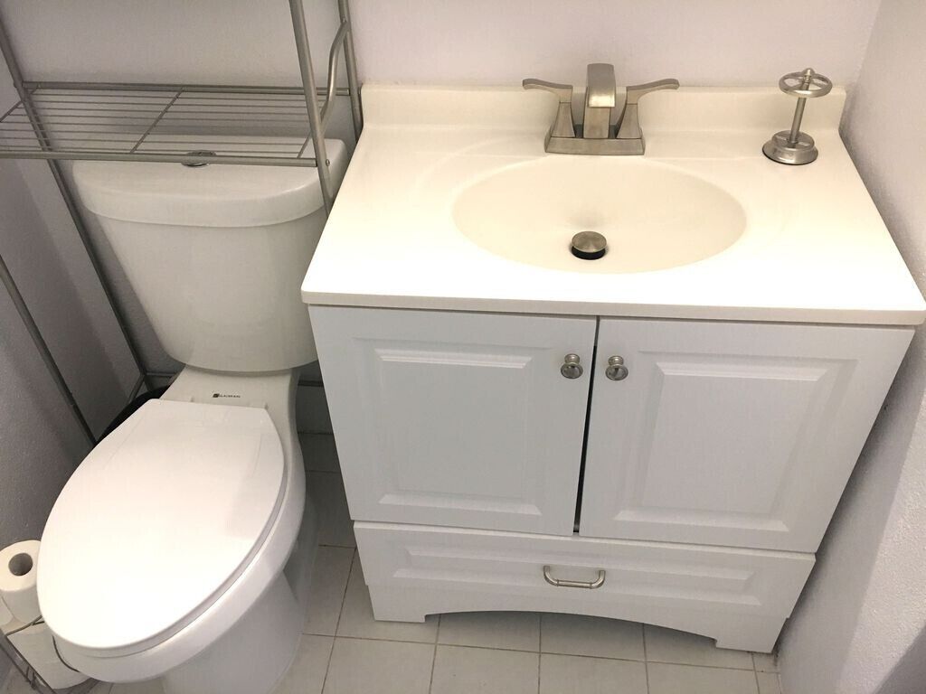 A bathroom with a toilet, a sink, and a cabinet.