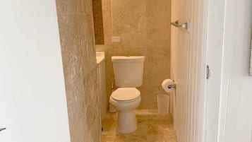 Een kleine badkamer met toilet, wastafel en betegelde vloer.