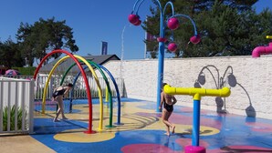 A water play area with colorful structures and a stone wall in the background. - Mobilhome INTUITION pond view, 4 *, near Beauval Zoo and Loire castles  (Veuzain-sur-Loire)