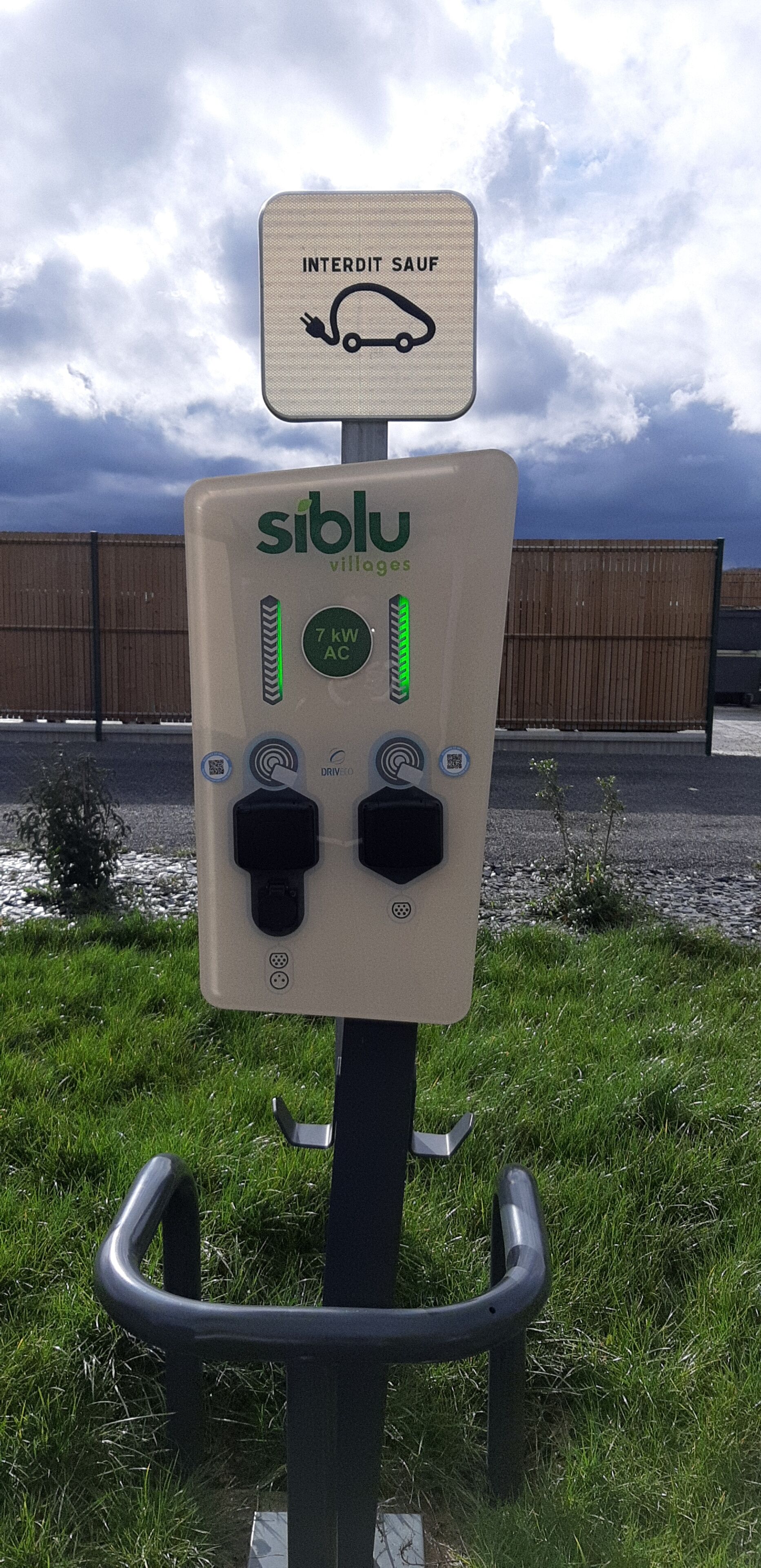 A portable electric vehicle charging station with a sign indicating 'INTERDIT SAUF' (except for electric vehicles).