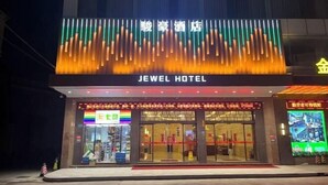 The exterior of the Jewel Hotel with a prominent sign, a storefront with various items on display, and a digital advertisement board. - Jewel Business Hotel (Kaiping)