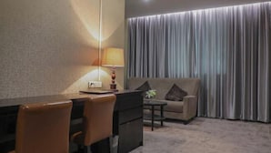 A hotel room with a desk, chairs, a sofa, and a lamp. - Jewel Business Hotel (Kaiping)