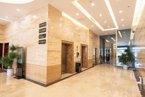 A hotel lobby with a marble reception desk, a plant, and a sign indicating the location. - Jewel Business Hotel (Kaiping)