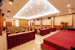 A conference room with rows of chairs, a stage with a red carpet, and a podium. - Jewel Business Hotel (Kaiping)