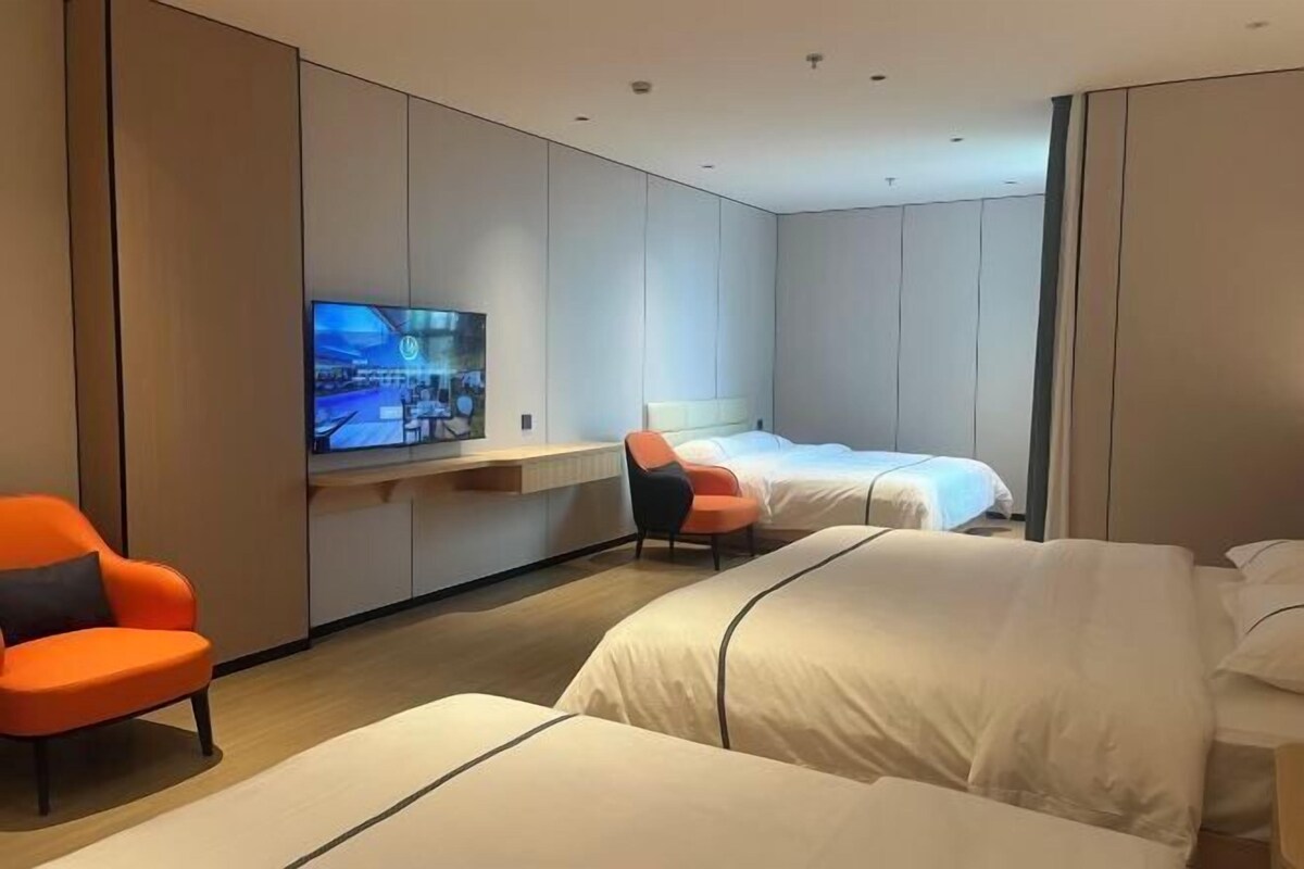 A hotel room with two beds, a TV mounted on the wall, and a desk with a chair.