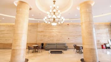 A lobby with two large columns, a chandelier, a sofa, and a coffee table.