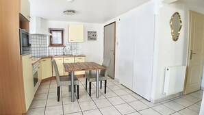 A compact kitchen with a dining area, a built-in oven, and a tiled backsplash. - L'Alsacienne - cosy gite (Eguisheim)