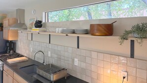 Una cocina moderna con estufa integrada, un fregadero y un ventanal con vistas a zonas verdes.