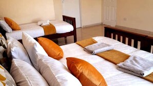 A hotel room with two beds, each with white bedding and orange pillows. - Manacomfy - 14bed House - 4 Baths - Victoria Falls (Victoria Falls)