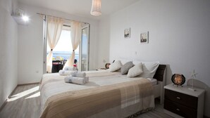A bedroom with a large bed, a bedside table, a nightstand, and a view of the sea. - Modern vacation apartment with pool and sea view (Pisak)