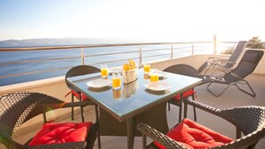 A dining table with chairs and a view of the sea. - Modern vacation apartment with pool and sea view (Pisak)